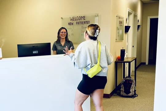 A patient at the front desk at OneHealth Chiropractic - Yukon, checking in for an appointment